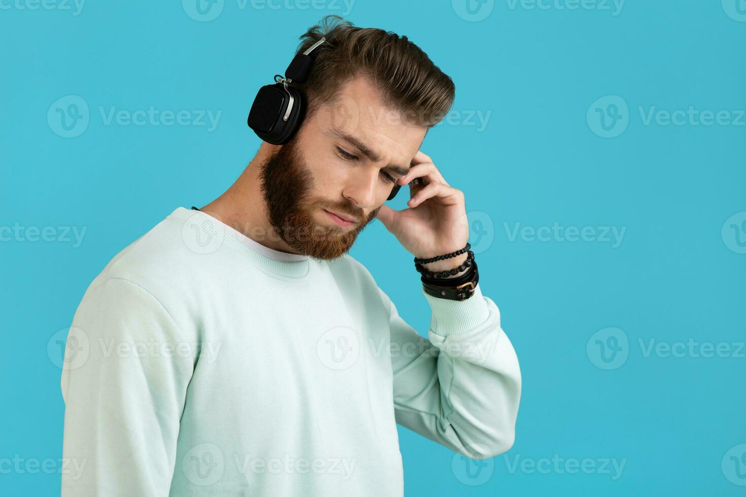 elegant jong Mens luisteren naar muziek- Aan draadloze hoofdtelefoons foto