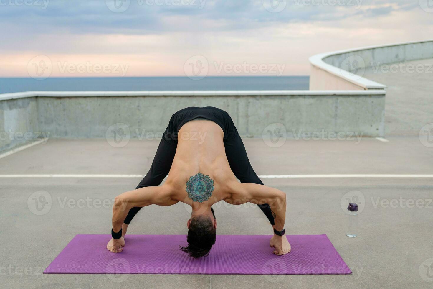 aantrekkelijk knap Mens met atletisch sterk lichaam aan het doen ochtend- yoga asana buitenshuis foto