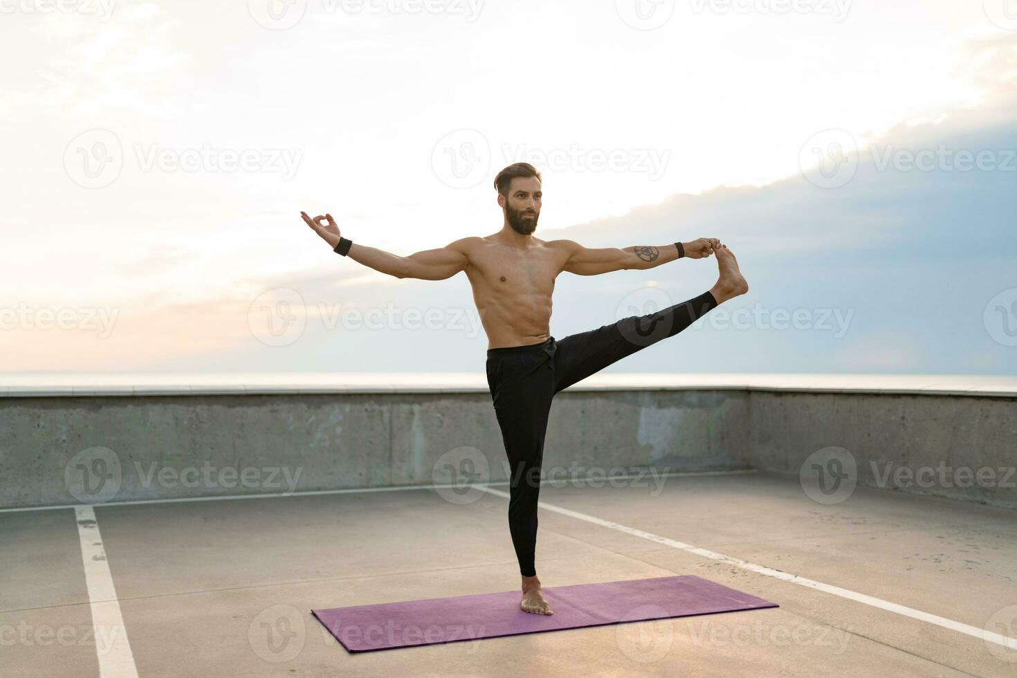 aantrekkelijk knap Mens met atletisch sterk lichaam aan het doen ochtend- yoga asana buitenshuis foto