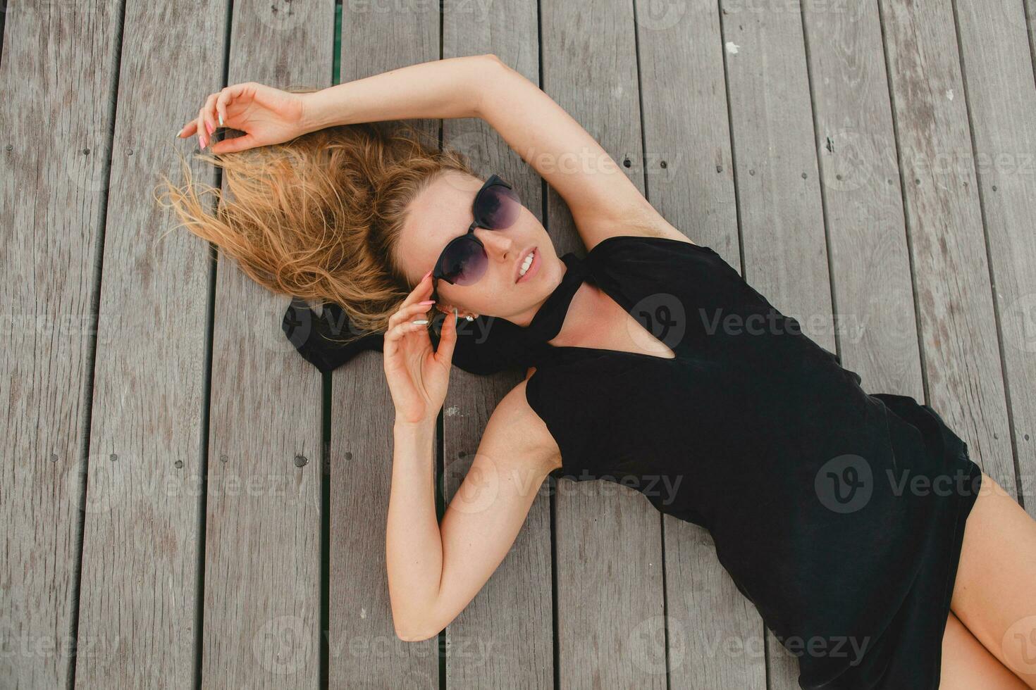luxe sexy aantrekkelijk vrouw gekleed in romantisch zwart jurk aan het liegen Aan verdieping foto