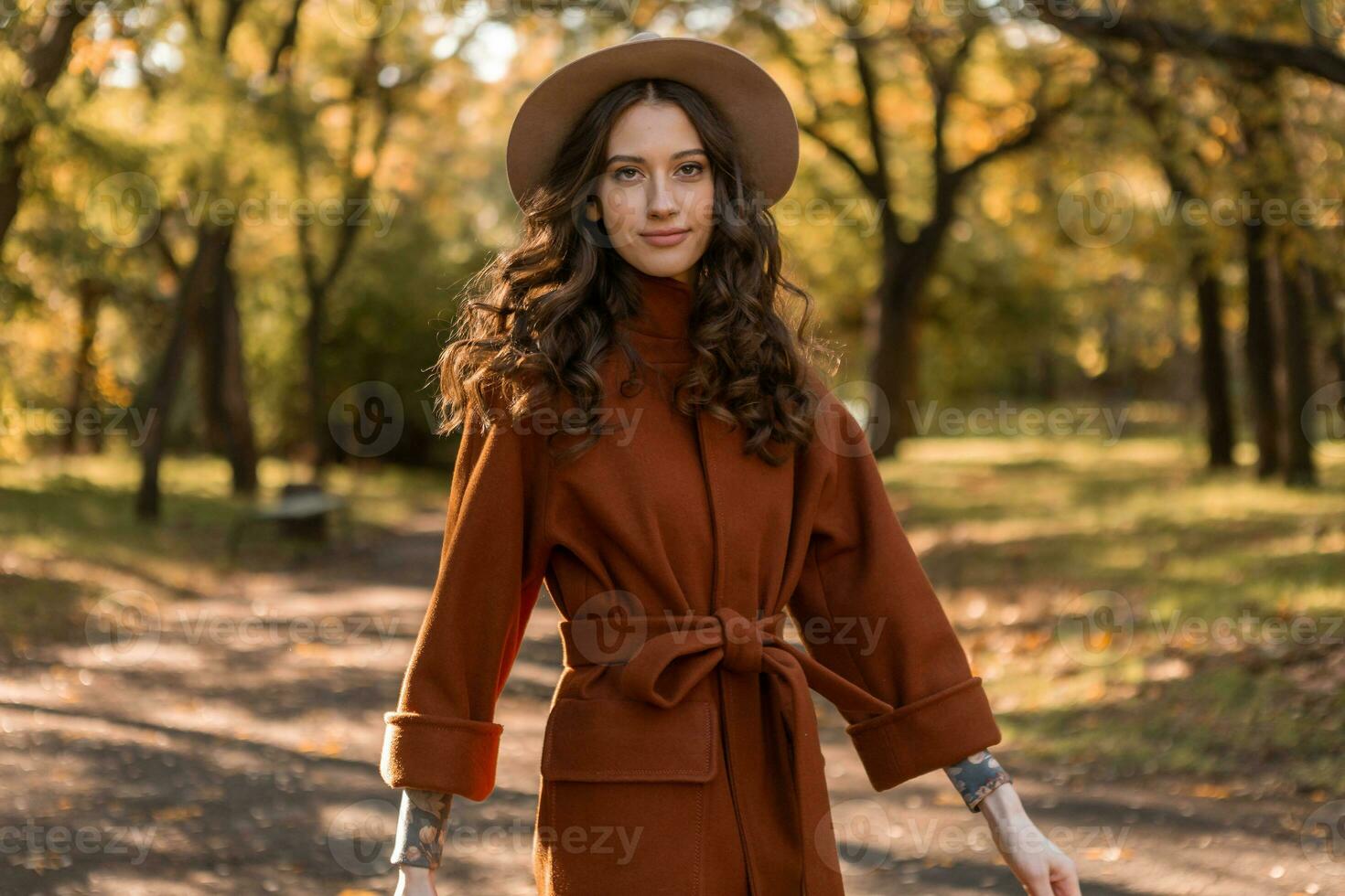 aantrekkelijk elegant vrouw wandelen in park gekleed in warm bruin jas foto