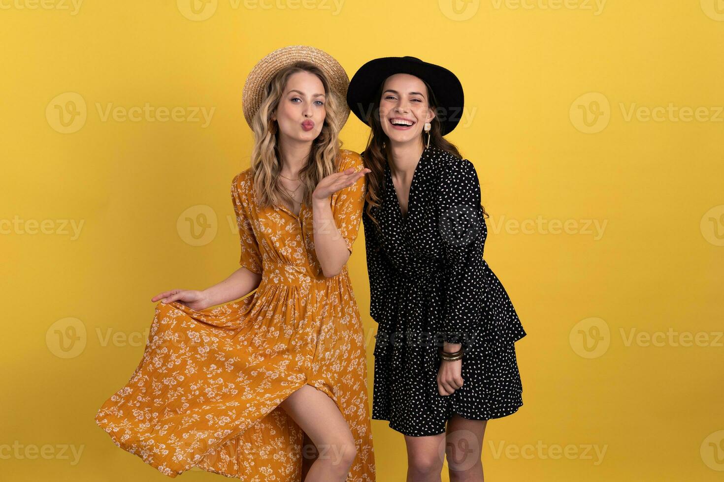 mooi Dames vrienden samen geïsoleerd Aan geel achtergrond in zwart en geel jurk en hoed foto