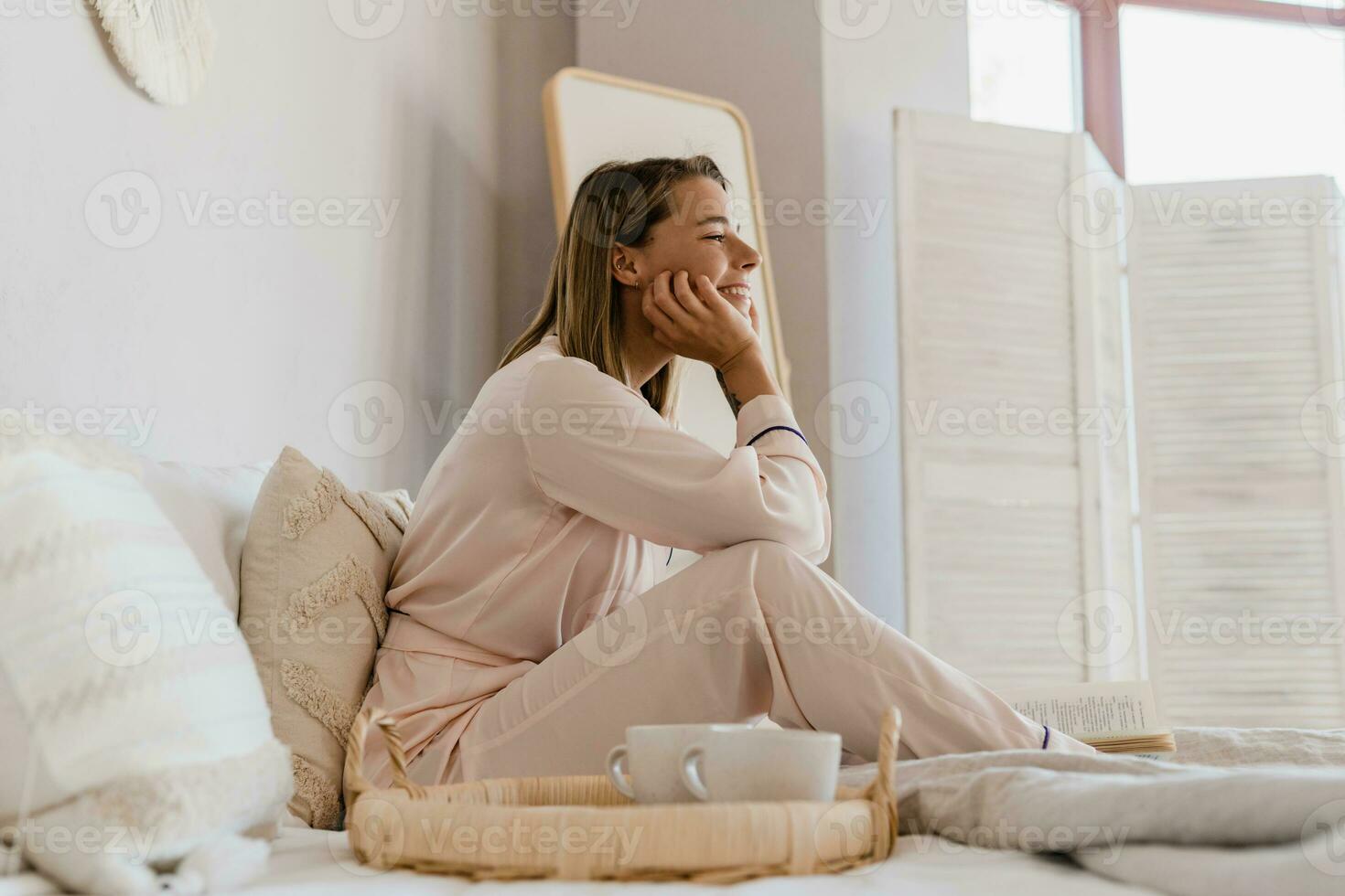 mooi glimlachen vrouw ontspannende Bij huis Aan bed in ochtend- in pyjama foto