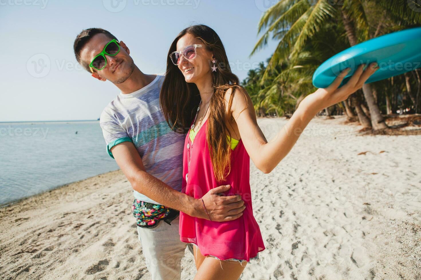 jong paar Mens en vrouw spelen vliegend schijf Aan tropisch strand, zomer vakantie foto