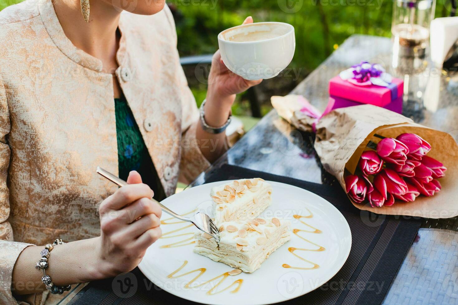 jong elegant vrouw zittend in cafe, Holding drinken kop cappuccino, aan het eten smakelijk taart foto