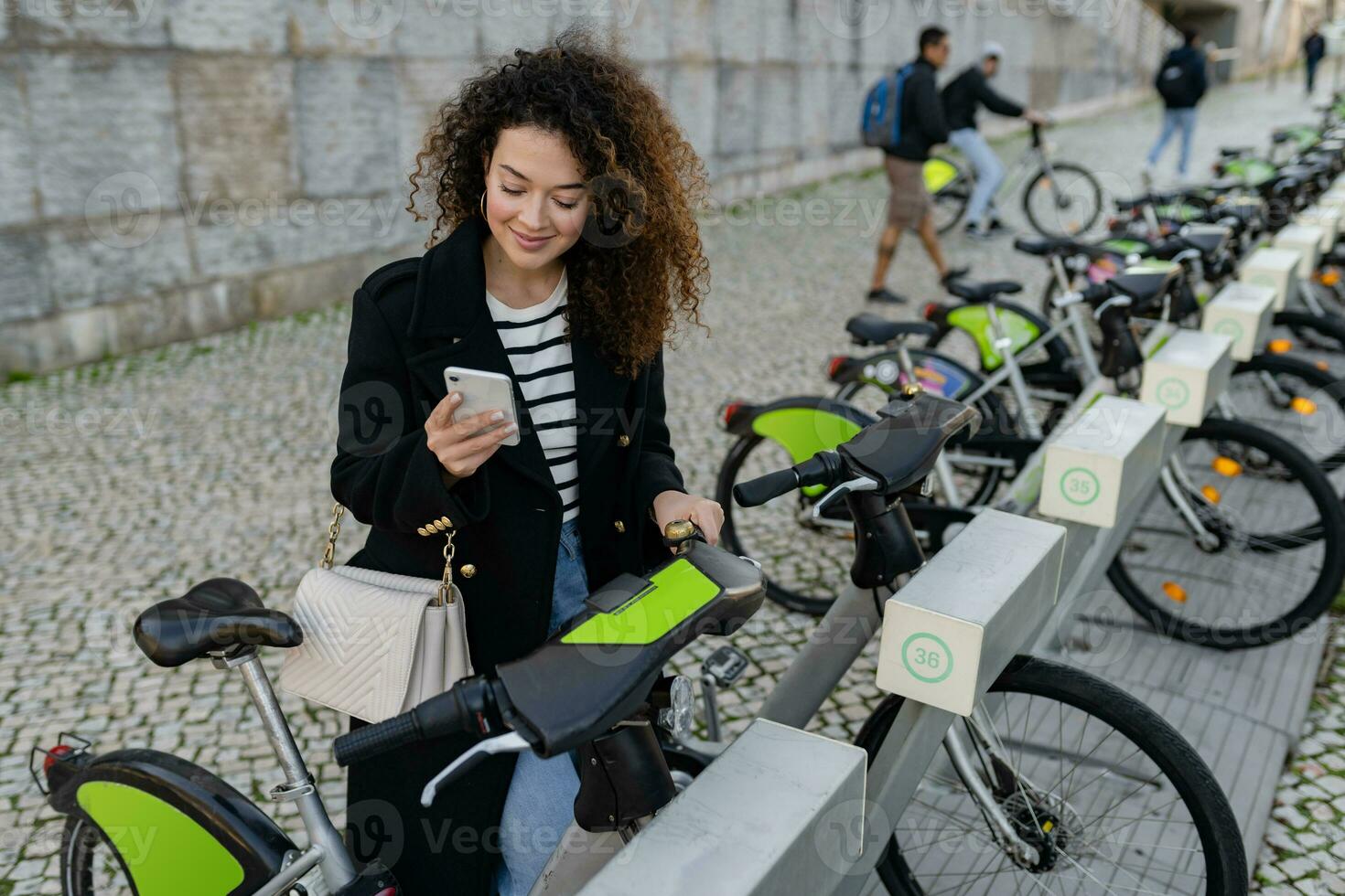 mooi gekruld vrouw huren een fiets in straat met een app foto