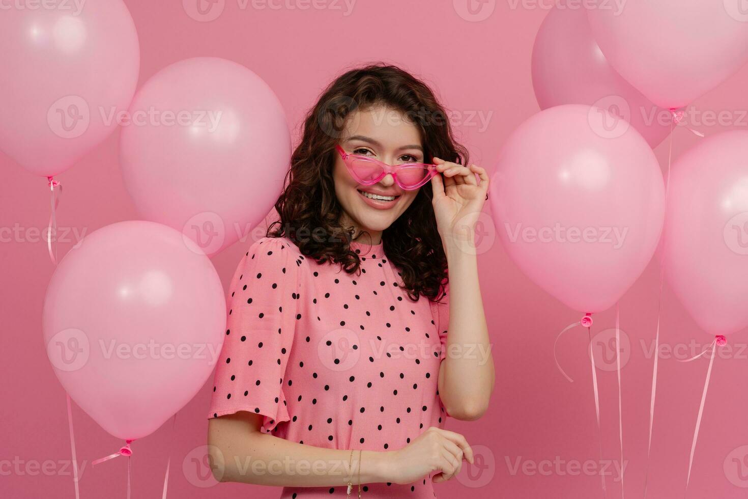 mooi jong vrouw poseren geïsoleerd Aan roze studio achtergrond met roze lucht baloons foto
