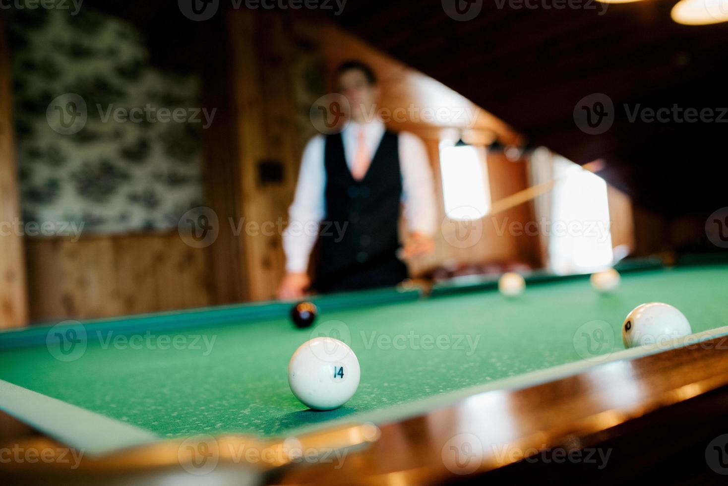 elegante jonge man in een donker pak speelt biljart foto