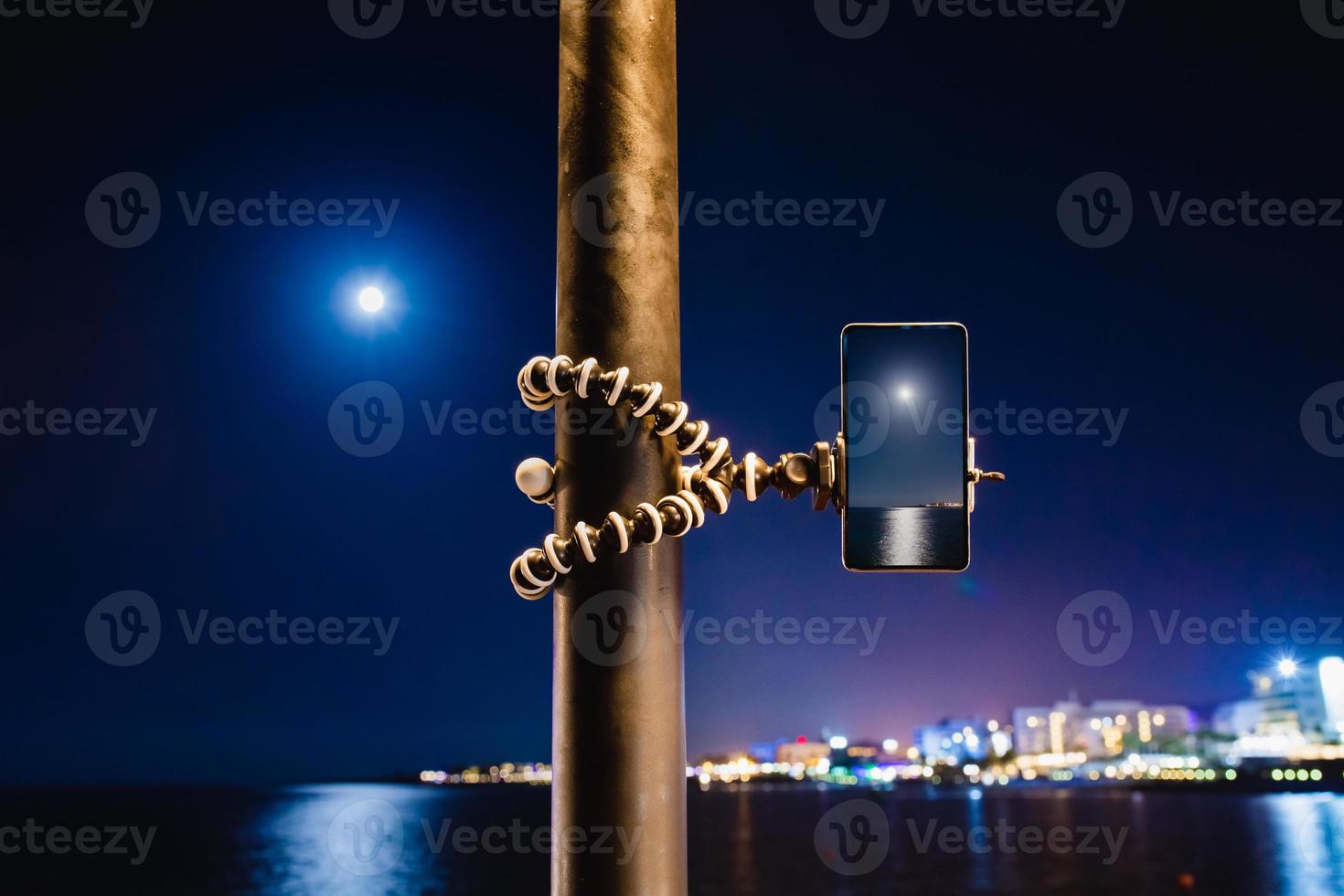 een smartphone gebruiken op een opvouwbaar statief met lange blootstelling aan de zee 's nachts foto