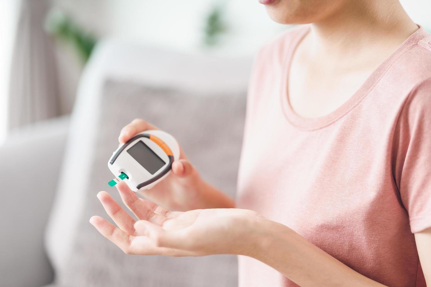 Aziatische vrouw die de bloedsuikerspiegel controleert door digitale glucosemeter, gezondheidszorg en medisch, diabetes, glycemieconcept foto