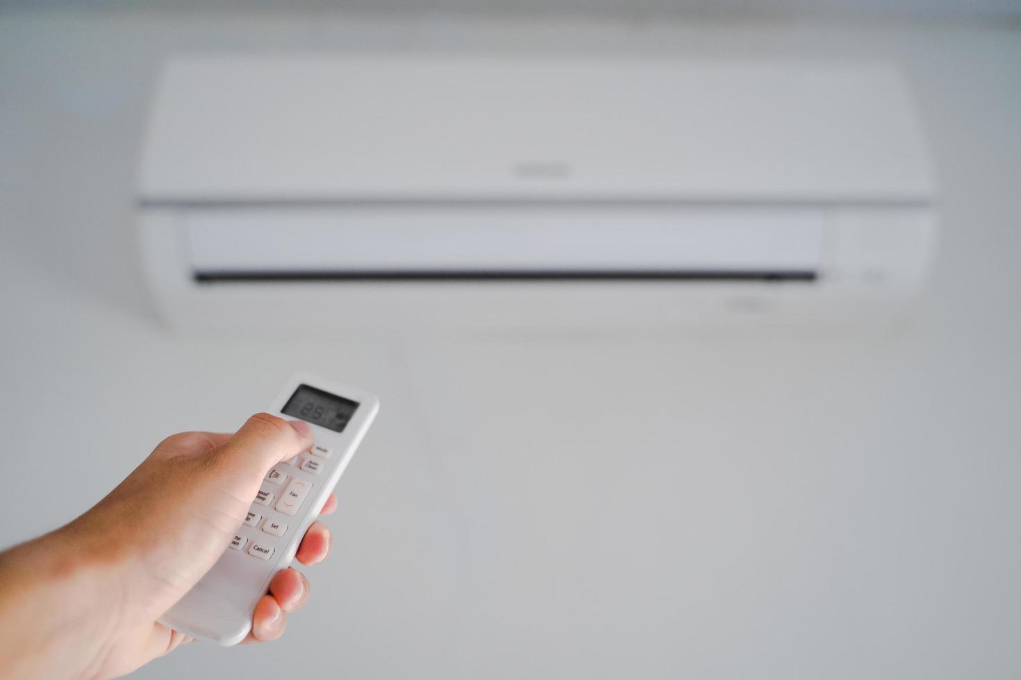 man handbediening afstandsbediening de airconditioner in de kamer. foto