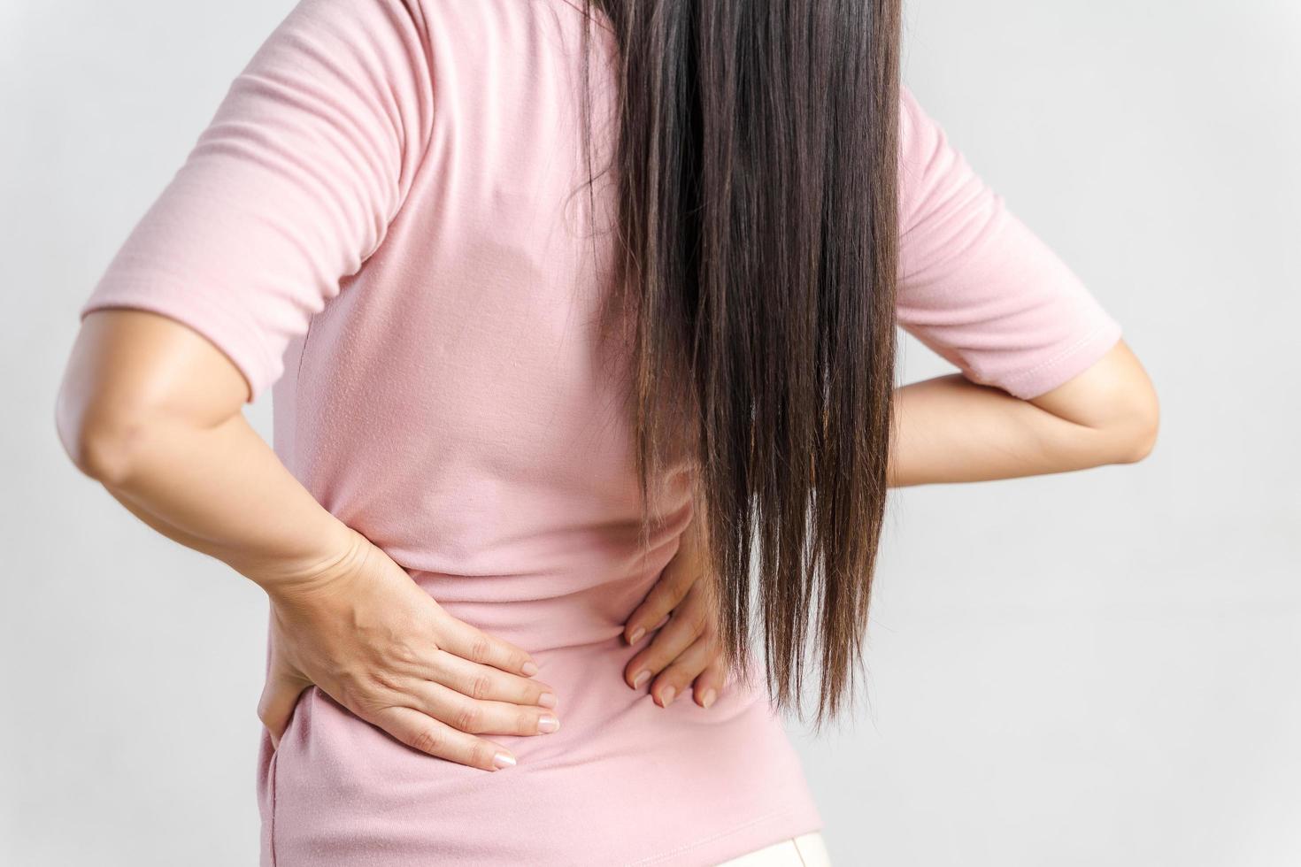 jonge vrouw die pijn in haar rug voelt op een witte achtergrond. gezondheidszorg en medisch concept. foto