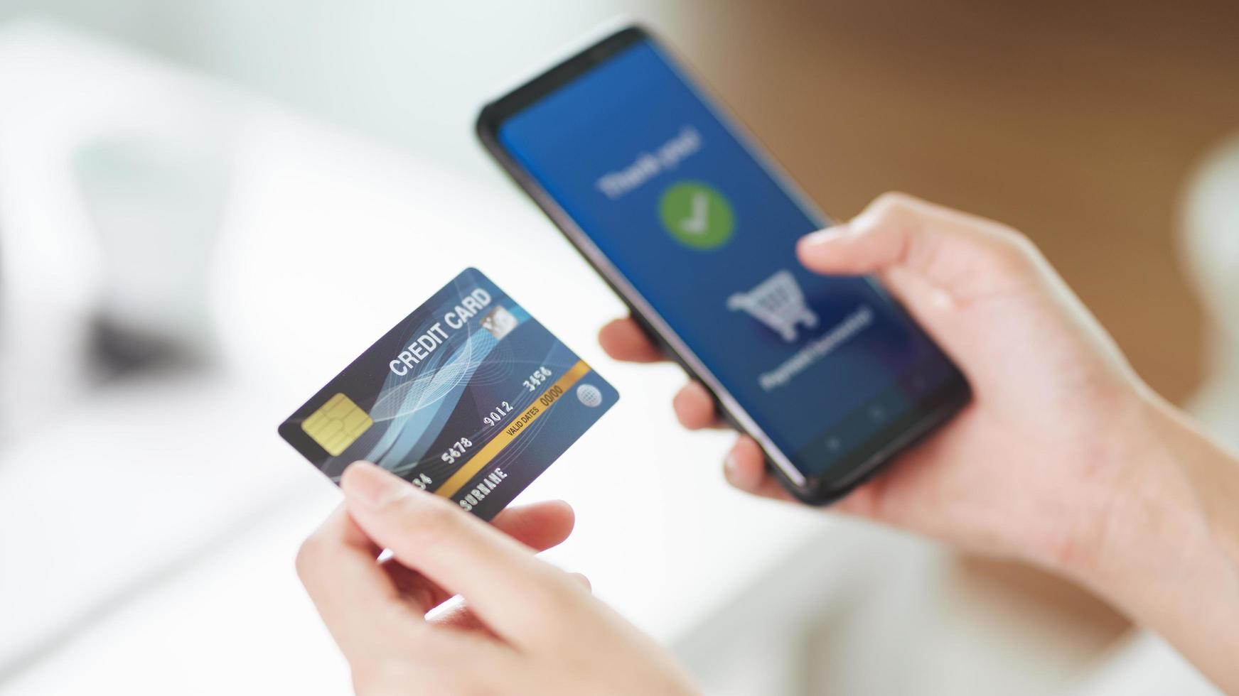 jonge vrouw met creditcard en het gebruik van slimme telefoon voor online winkelen, internetbankieren, e-commerce, geld uitgeven, thuiswerken concept foto