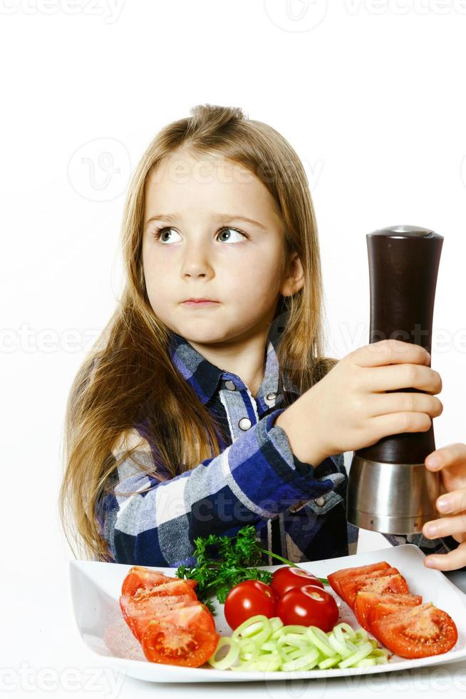 schattig klein meisje met salade en peperdoos foto