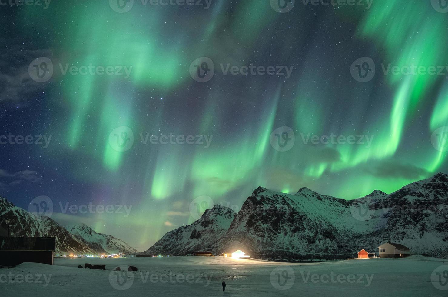 aurora borealis, noorderlicht over sneeuwberg en reiziger die in de winter loopt op de lofoten-eilanden foto