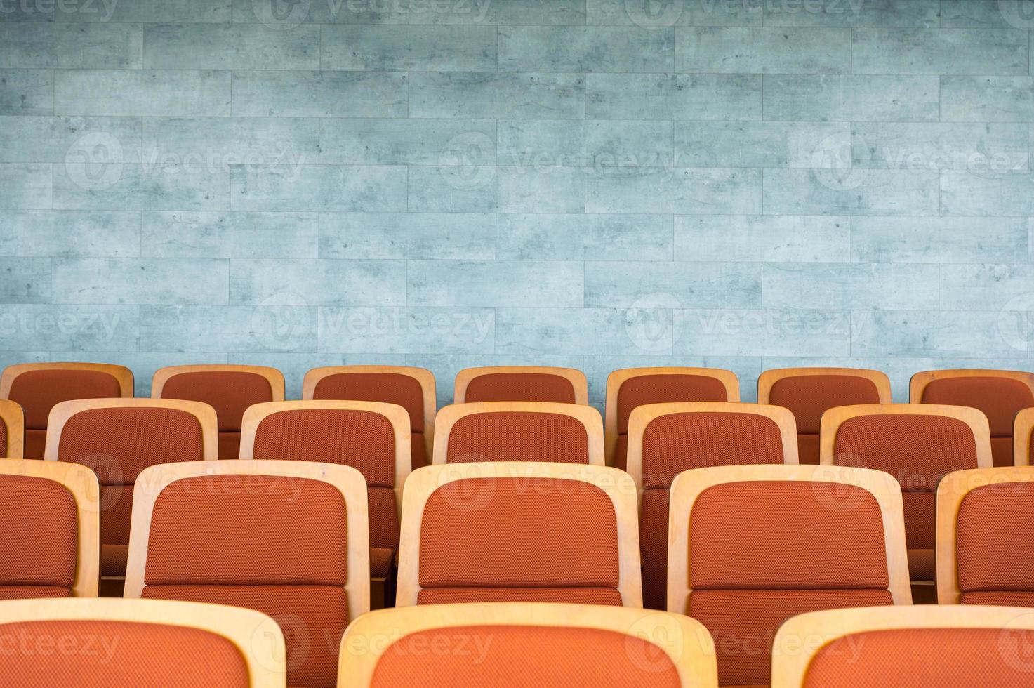 rij bruine theaterstoelen en marmeren muur in auditorium foto