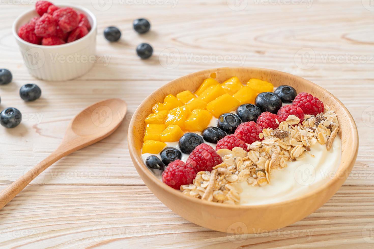 zelfgemaakte yoghurtkom met framboos, bosbes, mango en granola - gezonde voedingsstijl foto