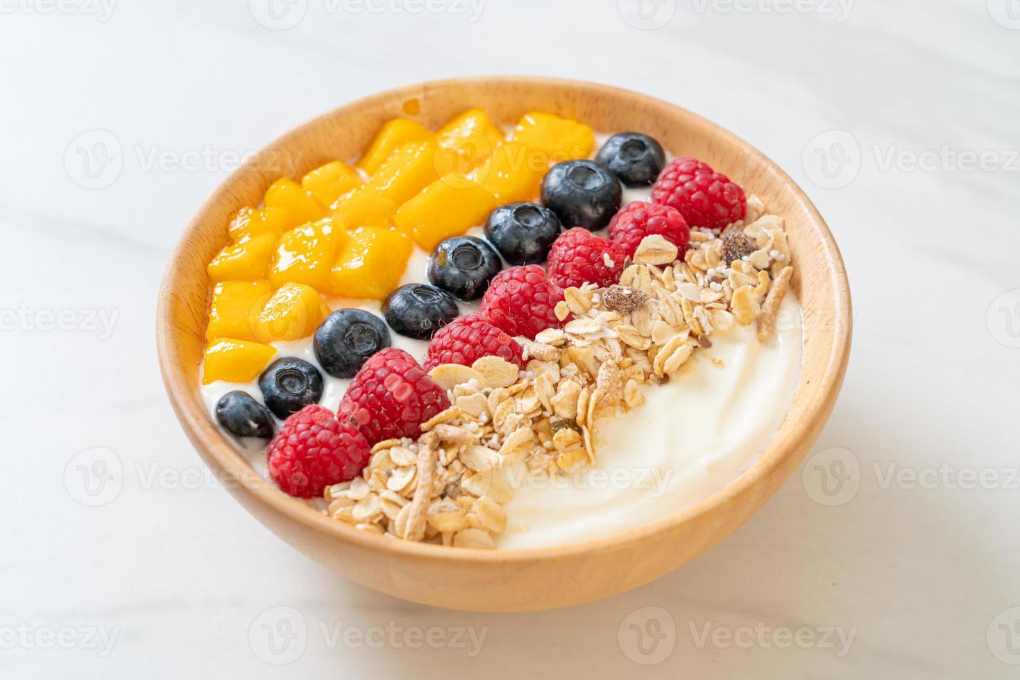 zelfgemaakte yoghurtkom met framboos, bosbes, mango en granola - gezonde voedingsstijl foto