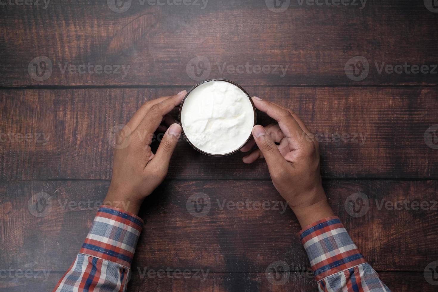 bovenaanzicht van iemands hand die verse yoghurt uit een kom eet foto