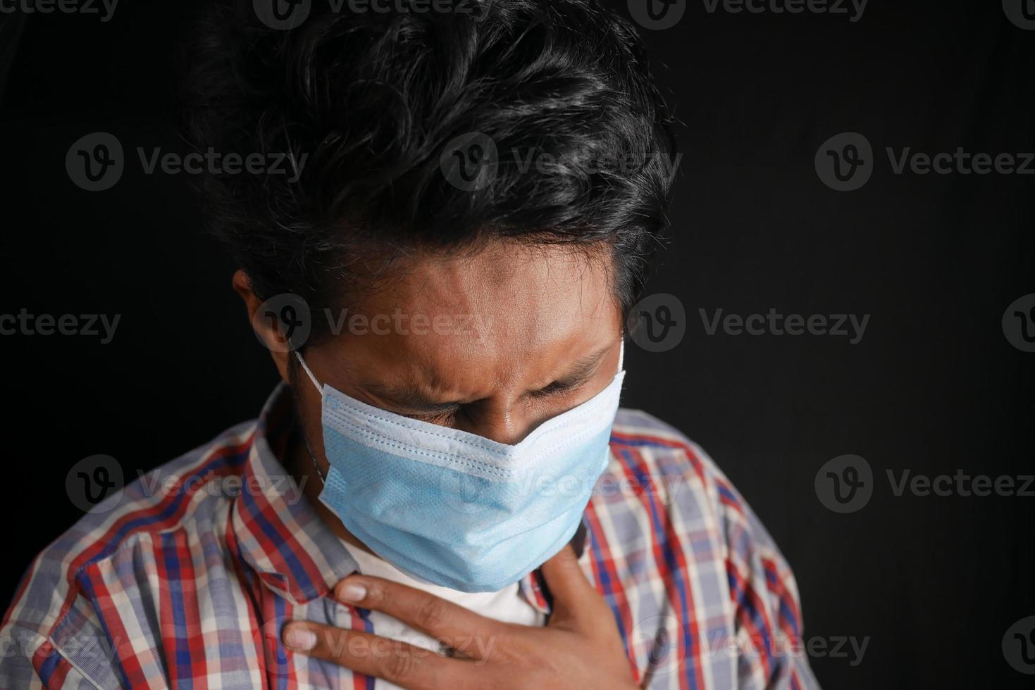 jonge zieke man hoesten en niezen geïsoleerd op zwart foto
