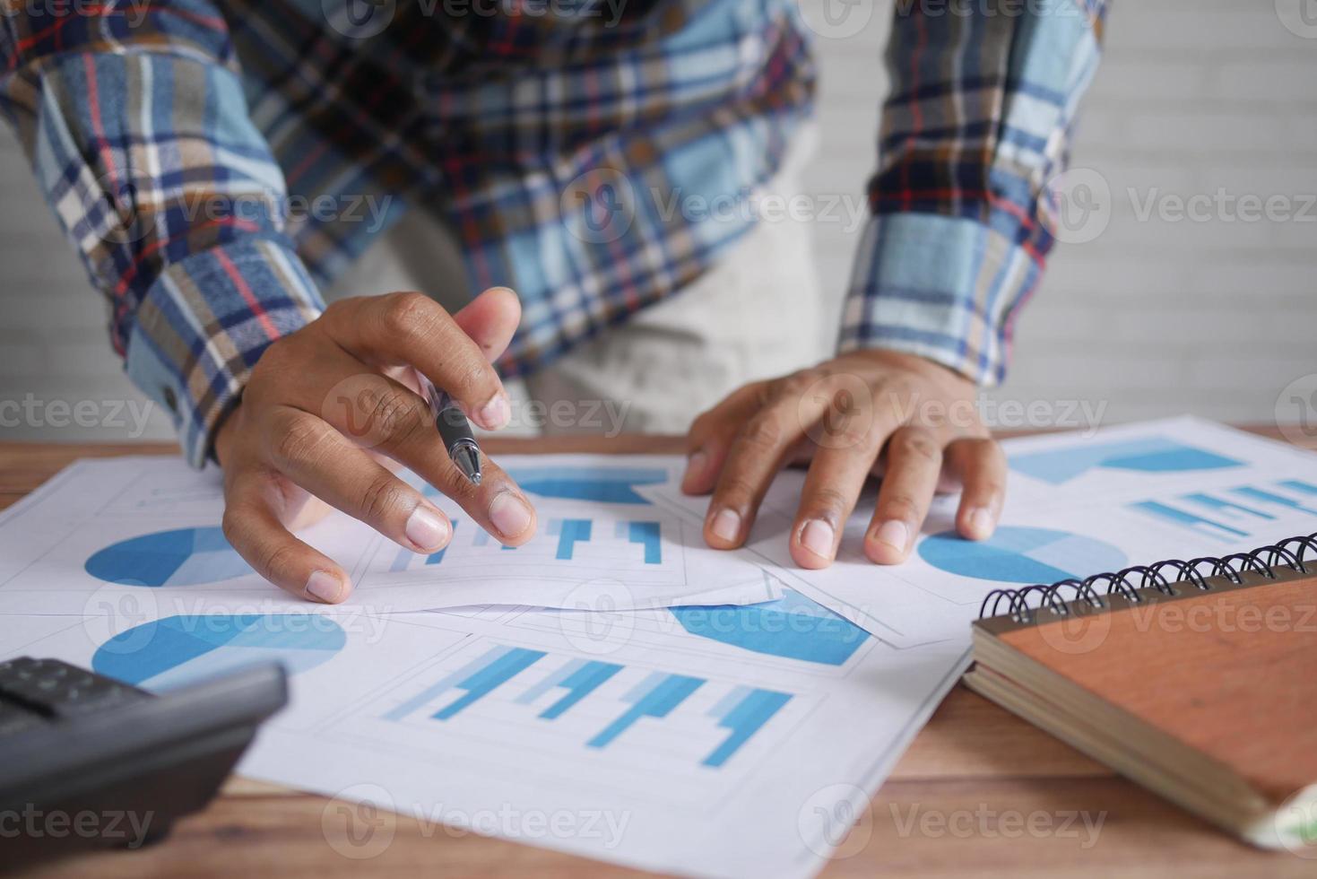 man hand met pen analyseren staafdiagram op papier en houden slimme telefoon holding foto