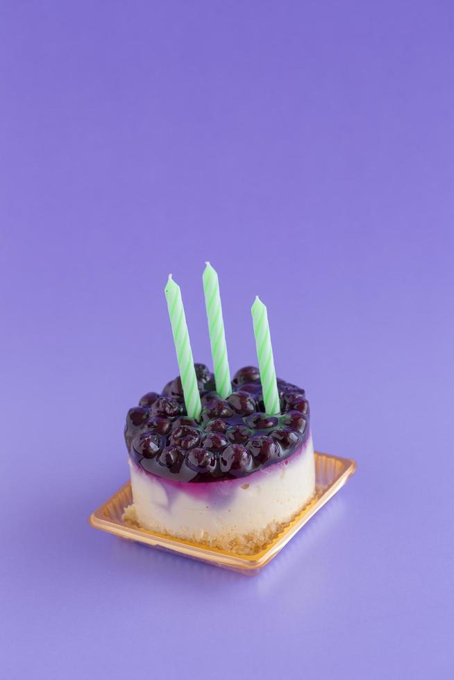 bosbessen cheesecake met kaarsen op een violette achtergrond foto