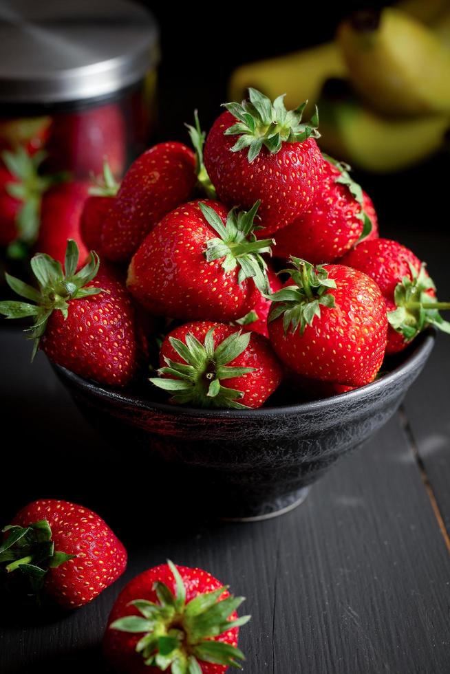 rijpe rode aardbeien op zwarte houten tafel foto