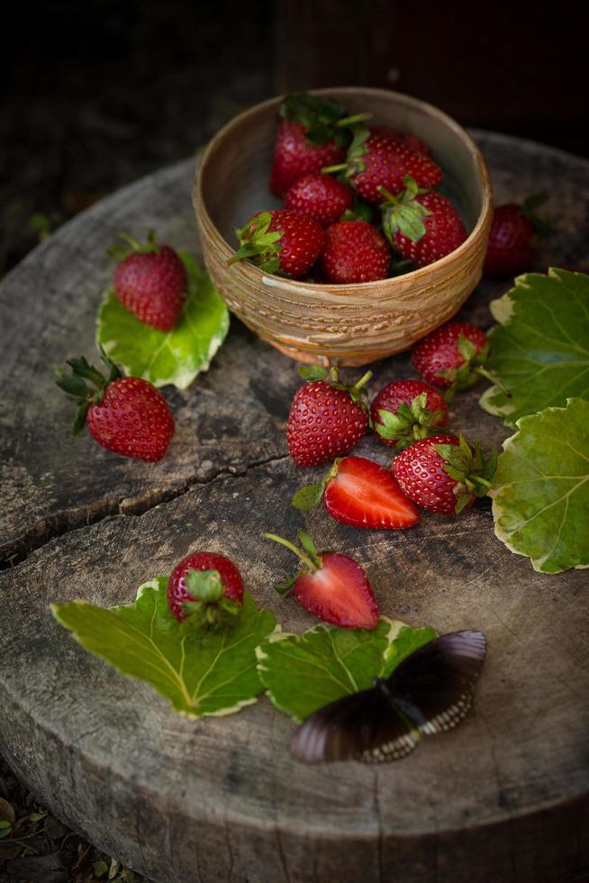 aardbei in een kom op een houten ondergrond foto