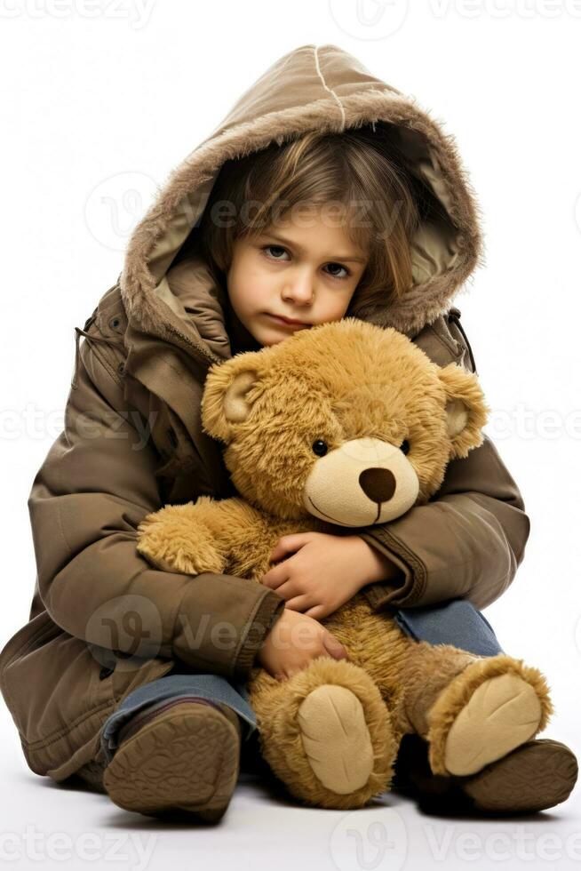 een eenzaam kind knuffelen een teddy beer voor comfort geïsoleerd Aan een wit achtergrond foto