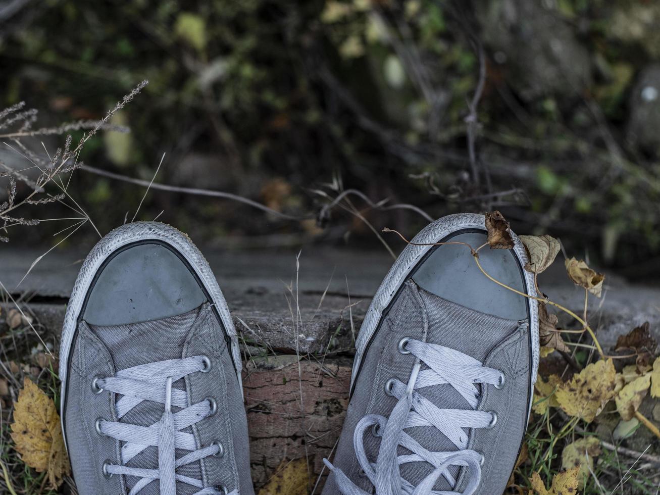grijze sneakers op de benen van een man tegen een achtergrond van herfstgebladerte foto