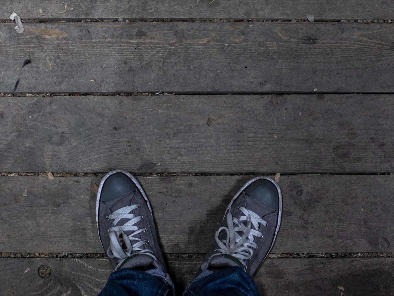 mannen voeten in sneakers staan op de houten vloer. modieuze herensneakers foto