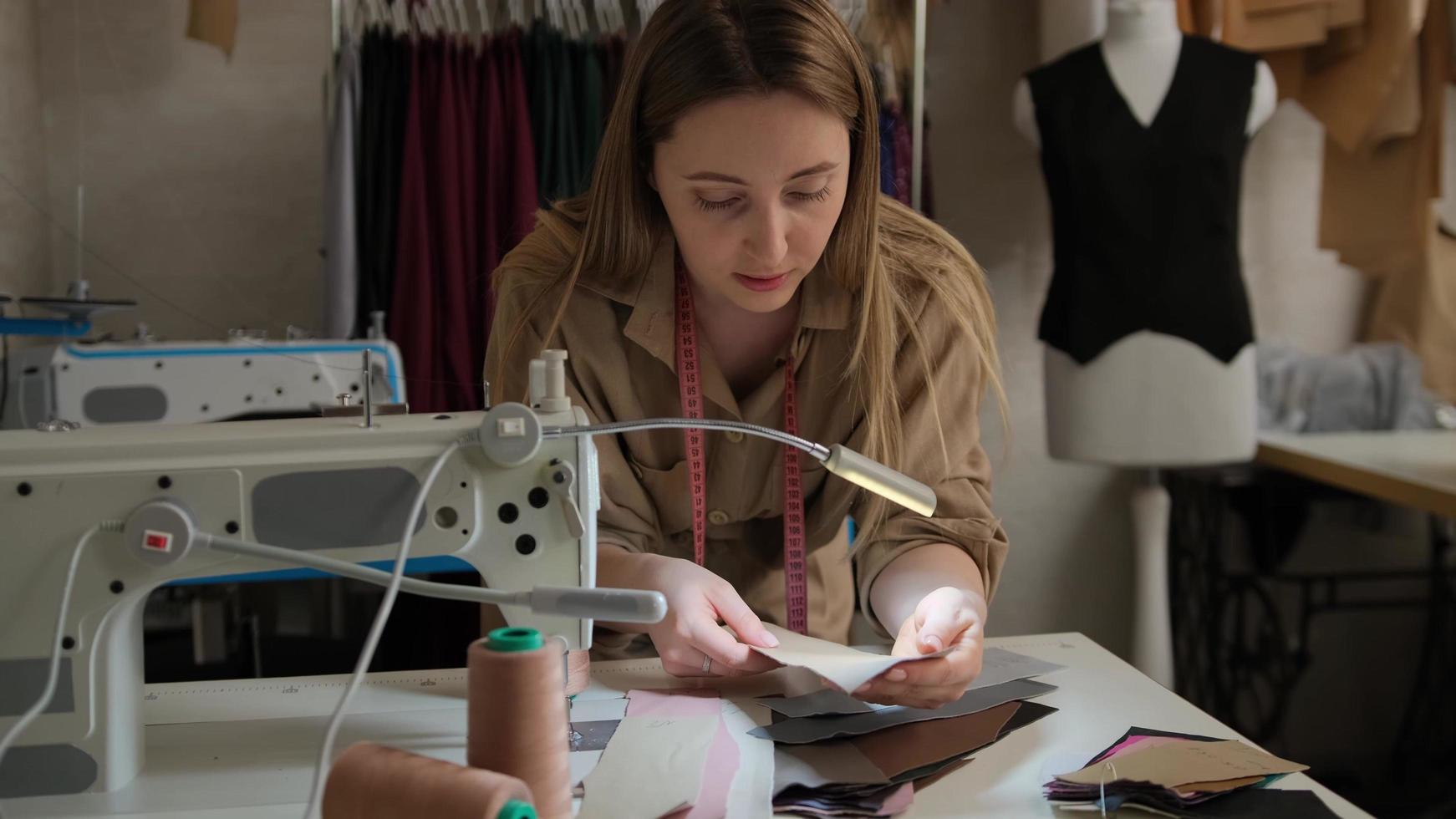 close-up van vrouwelijke kleermaker die een kleurrijk leerpatroon kiest dat door monsters gaat in de buurt van de naaimachine in de ontwerpstudio foto