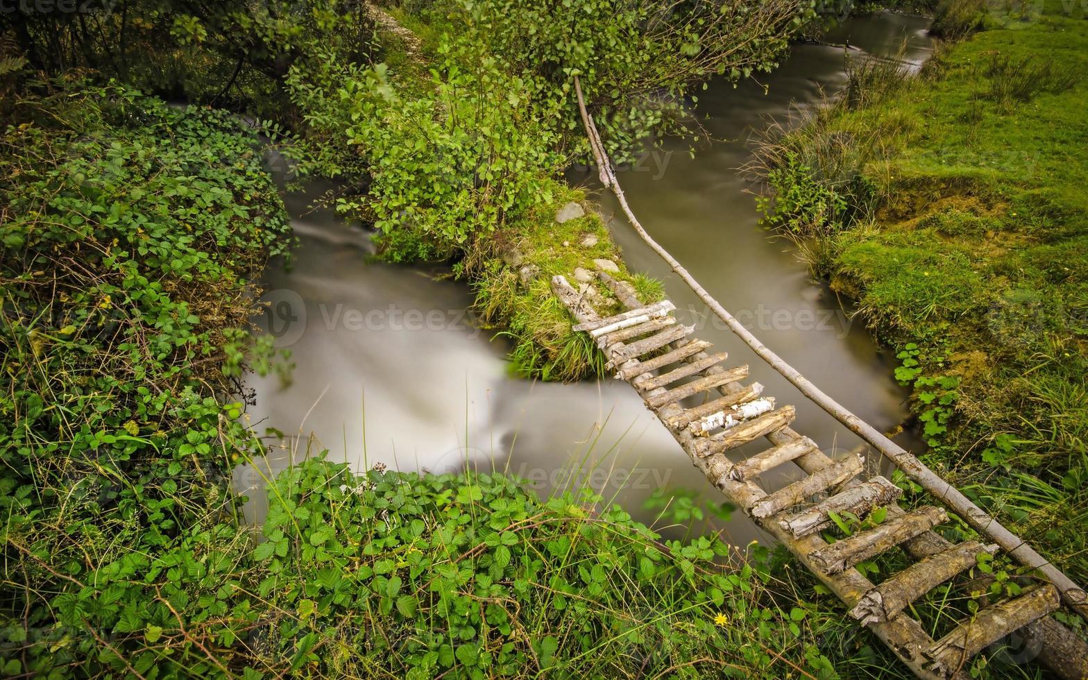 kleine landelijke voetgangersbrug over een kronkelige kreek foto