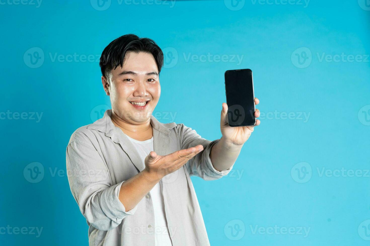 beeld van Aziatisch Mens gebruik makend van telefoon Aan blauw achtergrond foto