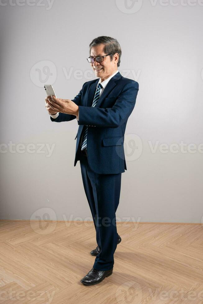 portret van een ouderen Aziatisch zakenman, poseren Aan een blauw achtergrond foto