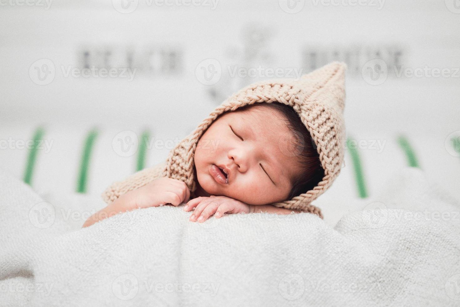 gelukkige schattige schattige Aziatische babyjongen met zwart haar liggend op een witte deken foto