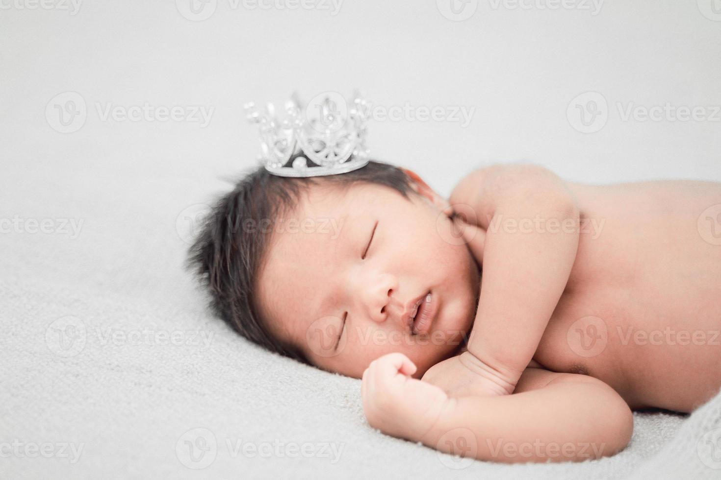 pasgeboren babyjongen die slaapt en een zilveren kroon draagt foto