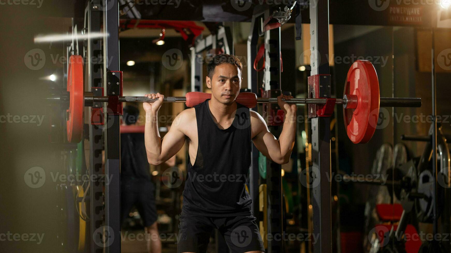 bodybuilding concept. portret van gespierd jong Aziatisch Mens opleiding met halters Bij Sportschool. zelfverzekerd Aziatisch bodybuilder werken uit met licht gewichten in geschiktheid foto