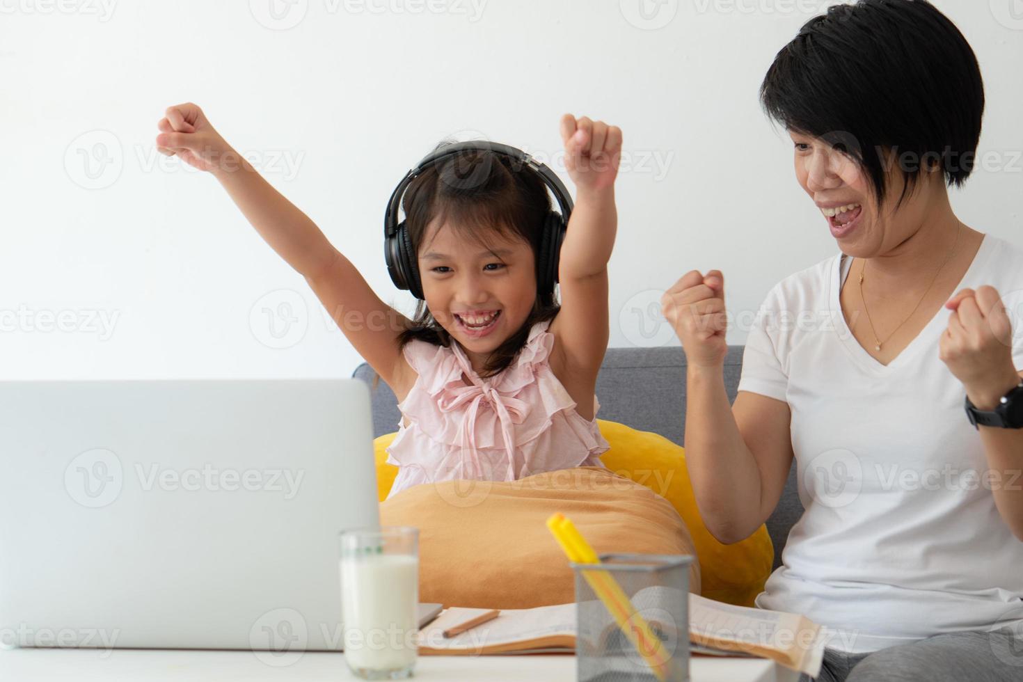 een Aziatische moeder geeft een jonge dochter les van de online computerles als thuisonderwijs vanwege covid-19 of een uitbraak van het coronavirus foto