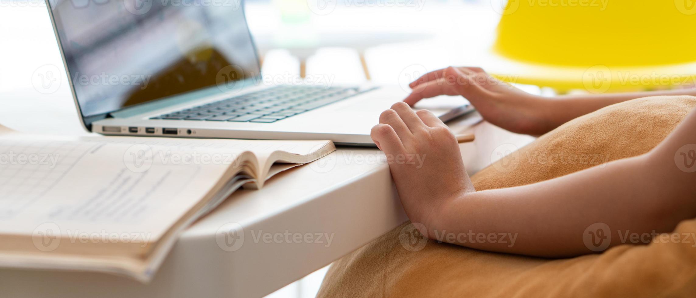 een jong Aziatisch meisje dat computer gebruikt om thuis te leren als protocol voor sociale afstand tijdens covid-19 of coronaviruspandemie. thuisonderwijs concept foto