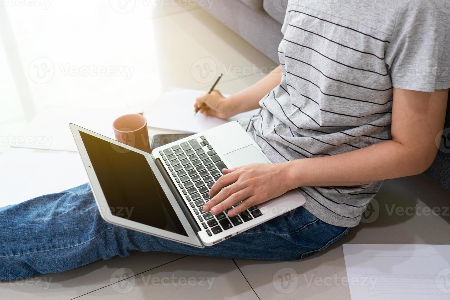 een freelance aziatische vrouw die computer gebruikt om 's ochtends vanuit huis in de woonkamer te werken tijdens covid-19 of coronaviruspandemie. nieuw normaal en technologisch concept foto