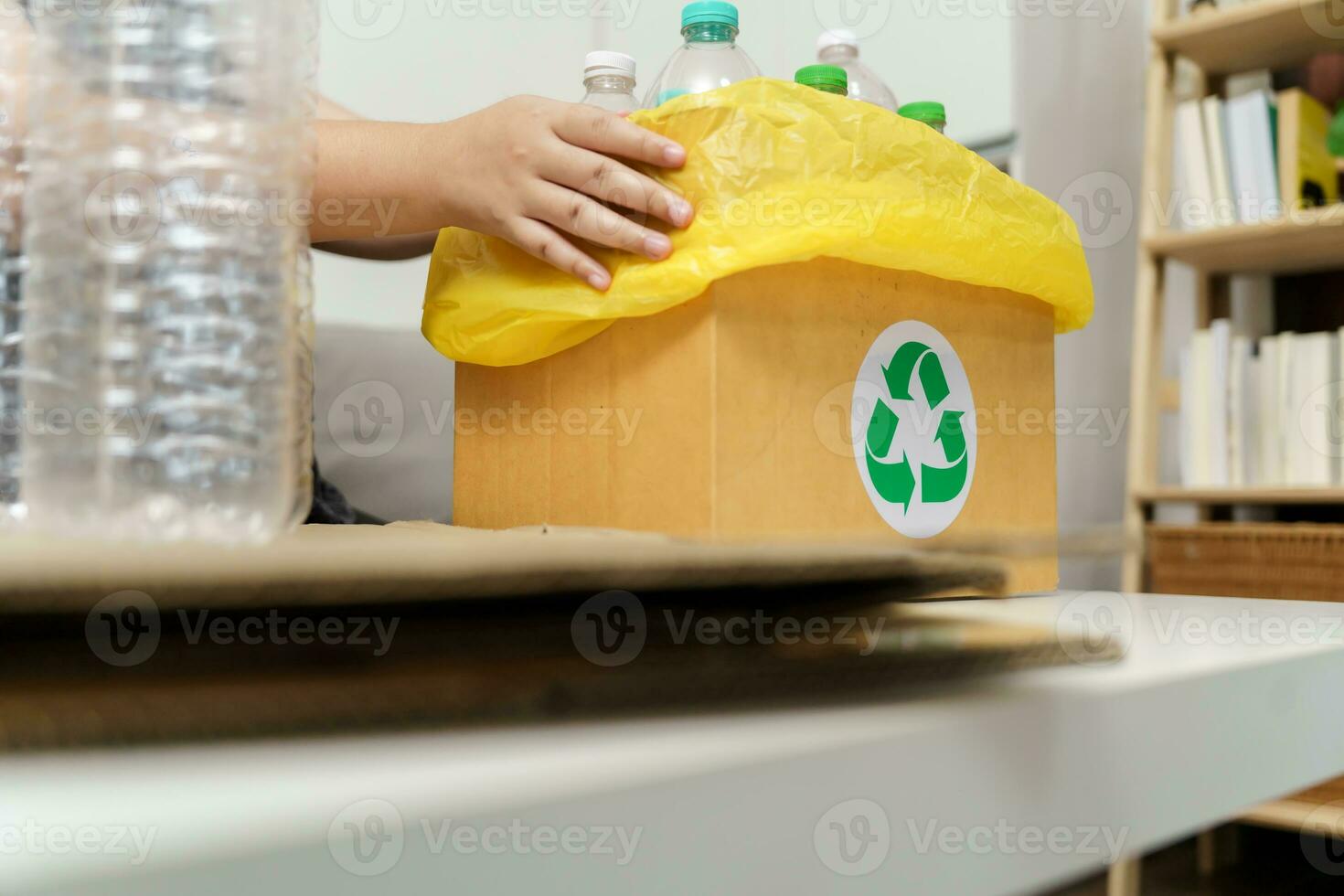 huis recycle eco groen nul concept vrouw het werpen leeg plastic fles in recycling bak met geel vuilnis Tassen Bij huis. foto