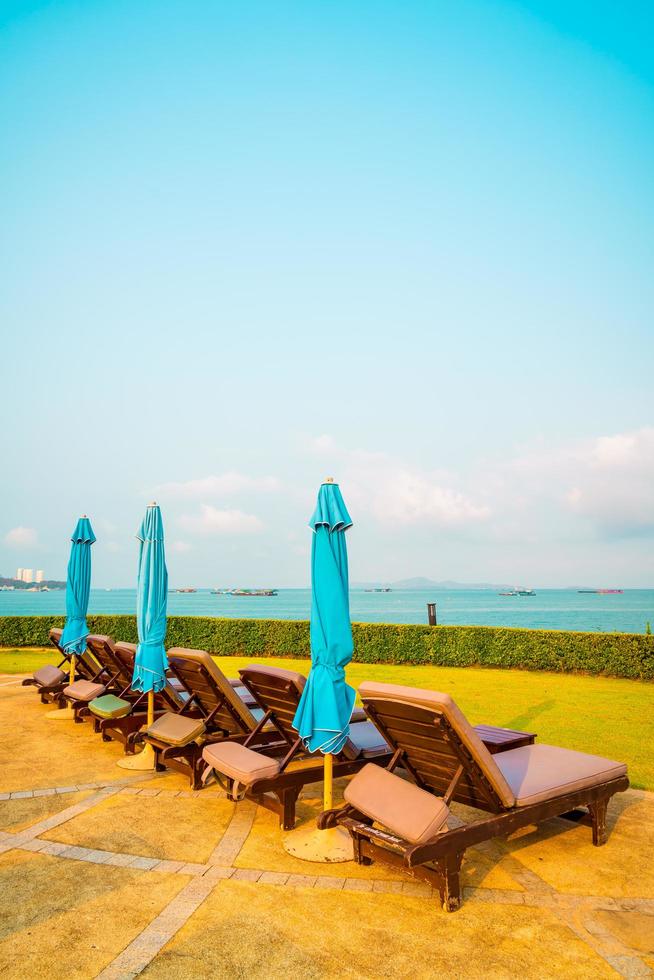stoel zwembad en parasol rond zwembad met oceaan zee achtergrond foto