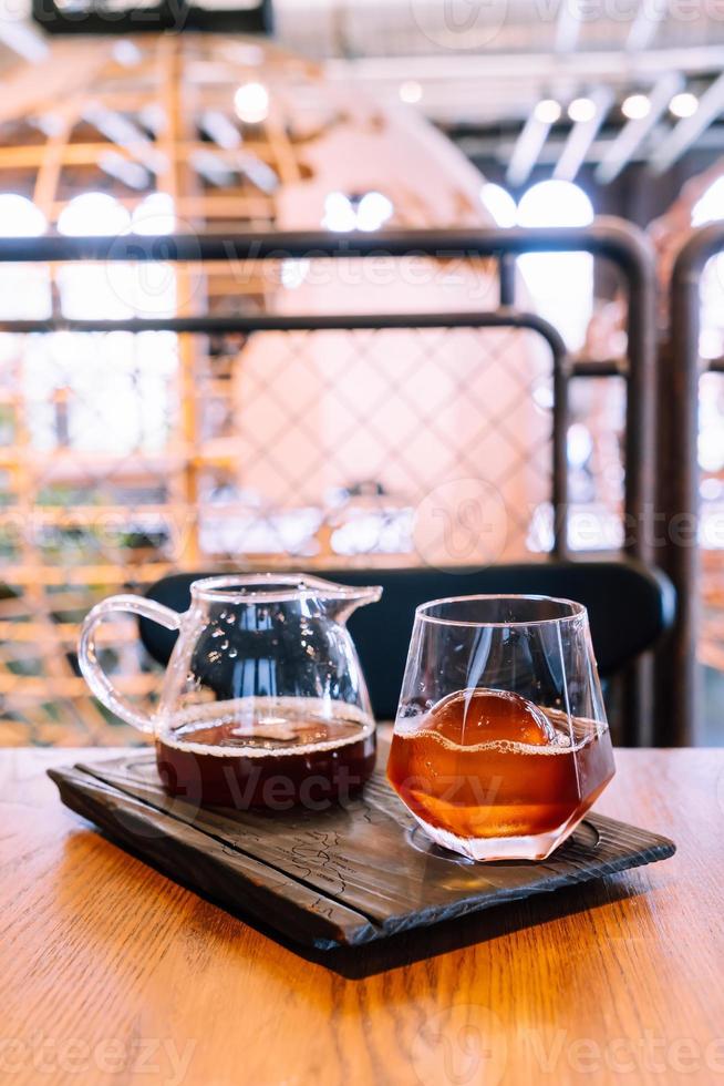 koude druppel zwarte koffiepot met glas en ijs in het café en restaurant van de coffeeshop foto