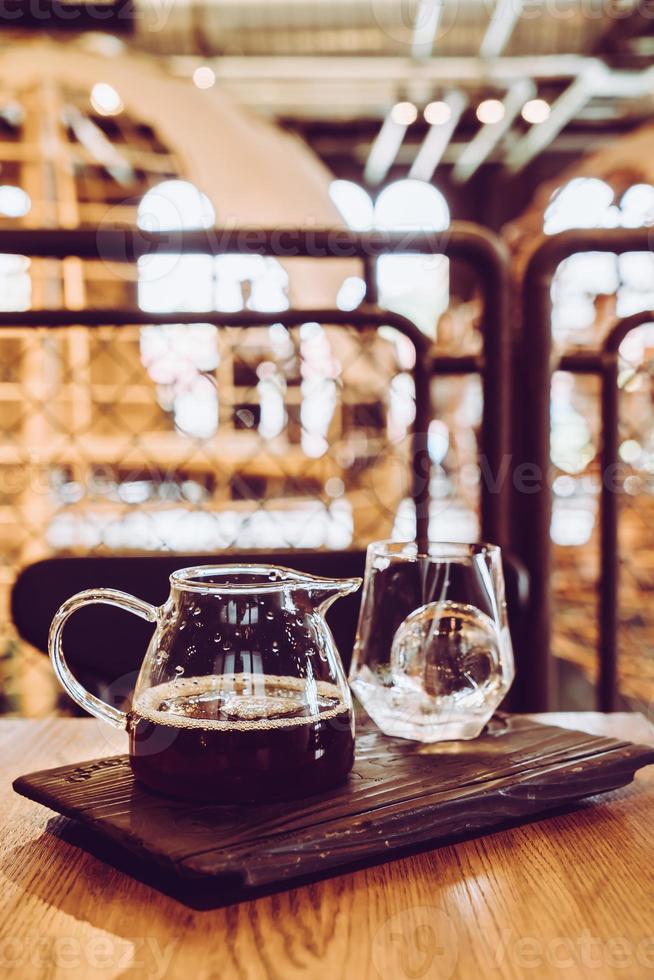 koude druppel zwarte koffiepot met glas en ijs in het café en restaurant van de coffeeshop foto