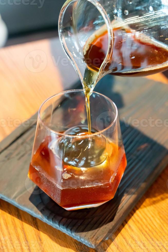 koude druppel zwarte koffiepot met glas en ijs in het café en restaurant van de coffeeshop foto