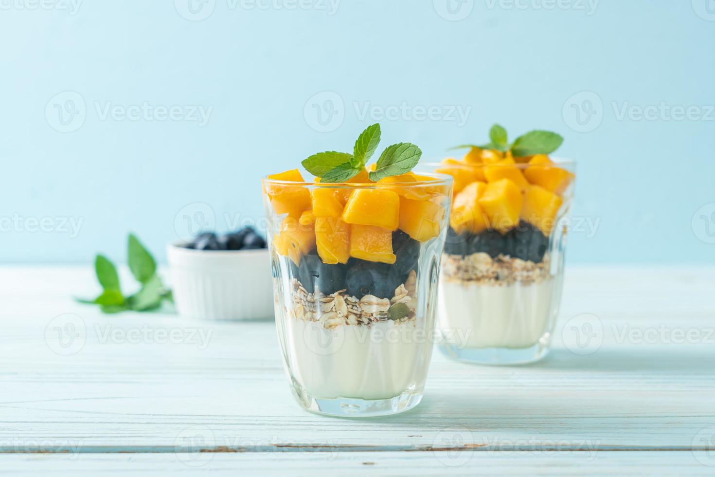 zelfgemaakte verse mango en verse bosbes met yoghurt en granola - gezonde voedingsstijl foto