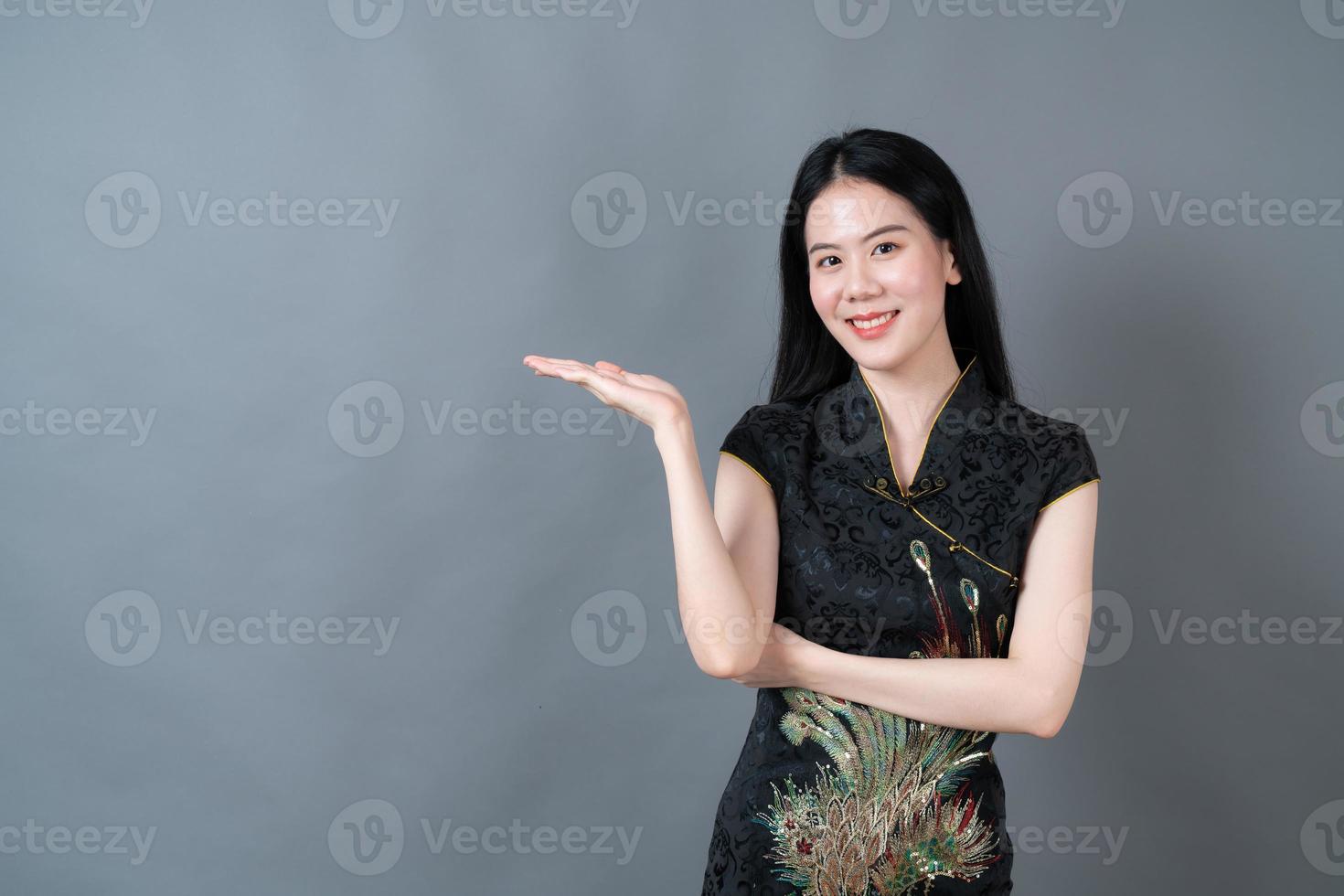 mooie jonge aziatische vrouw draagt chinese traditionele kleding met hand presenteren aan de zijkant foto