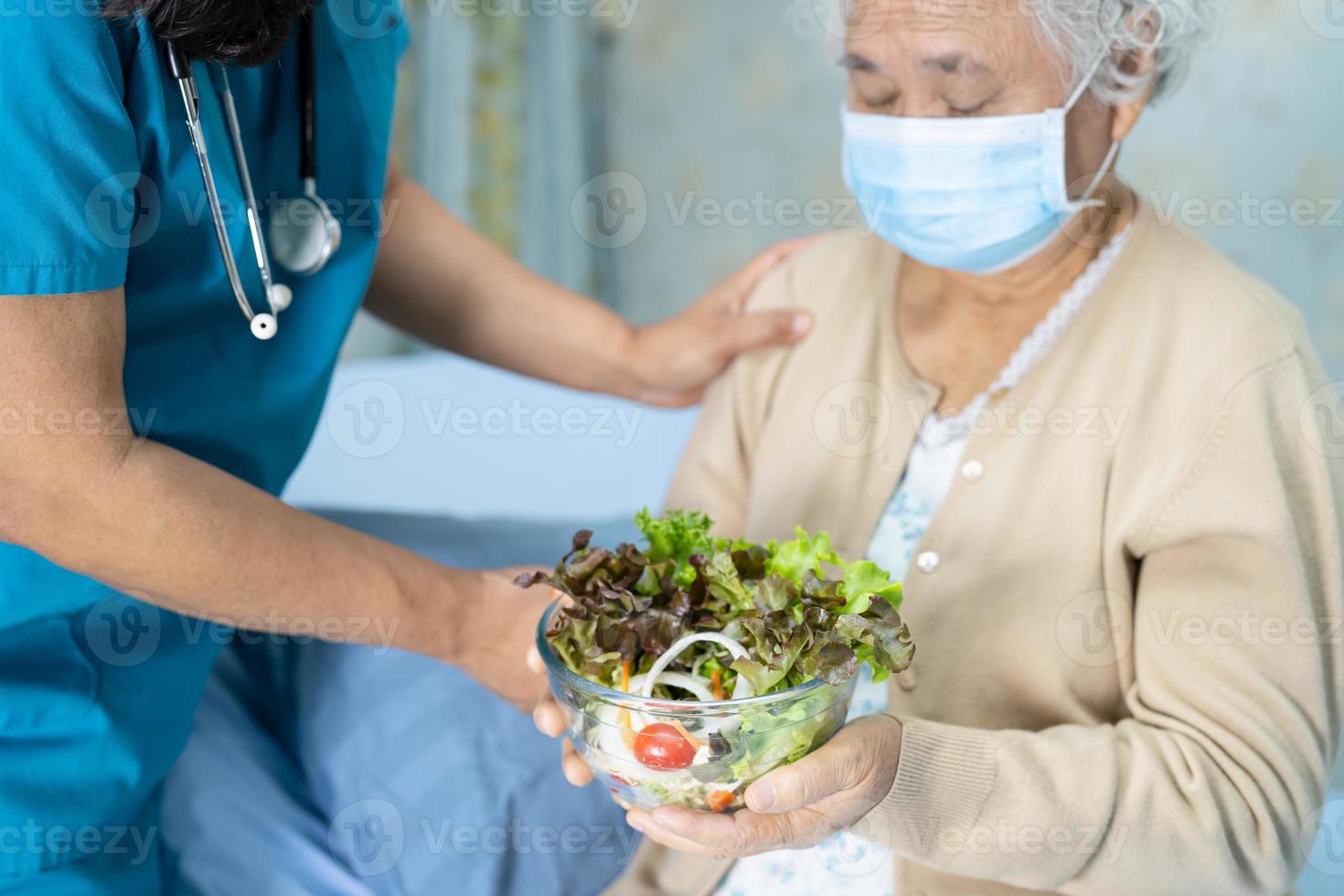 Aziatische senior of oudere oude dame vrouw patiënt ontbijt plantaardig gezond voedsel eten met hoop en gelukkig zittend en hongerig op bed in het ziekenhuis. foto