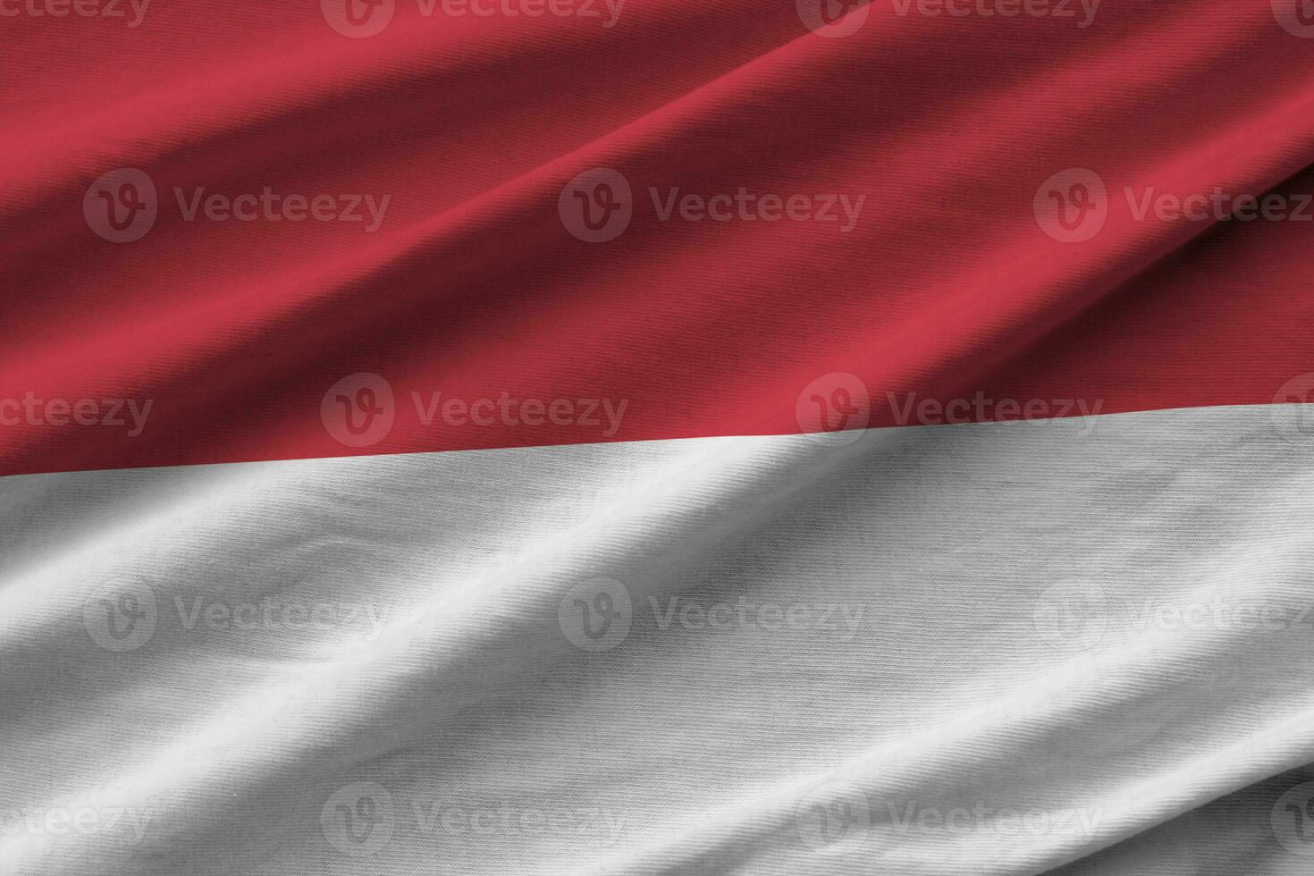 Indonesië vlag met groot vouwen golvend dichtbij omhoog onder de studio licht binnenshuis. de officieel symbolen en kleuren in banier foto